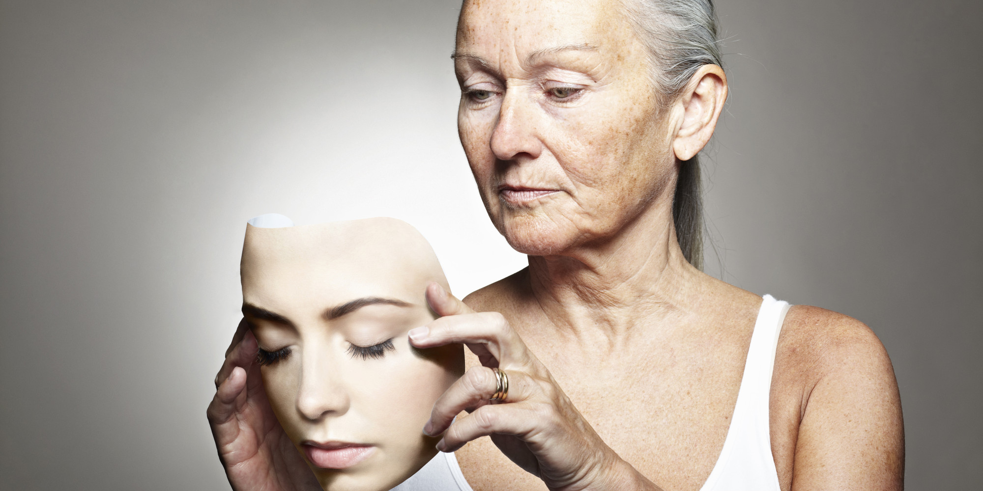 Older woman holding young mask